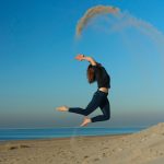 Photo d'une femme sautant et jetant du sable sur une plage