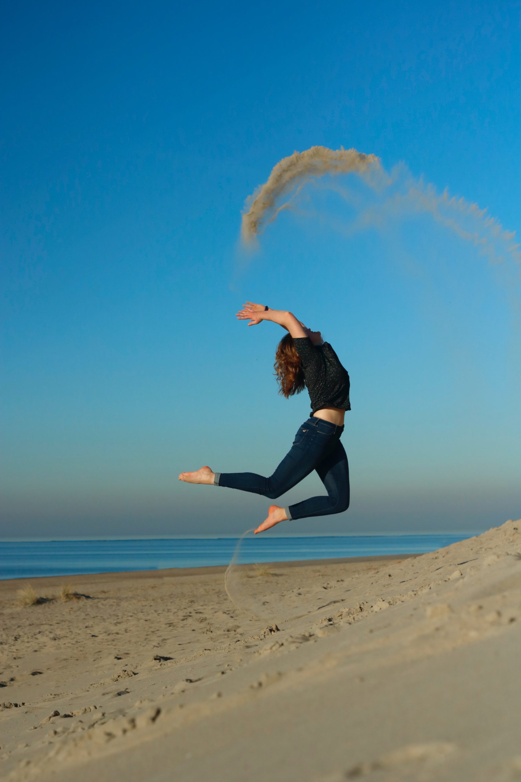 Photo d'une femme sautant et jetant du sable sur une plage